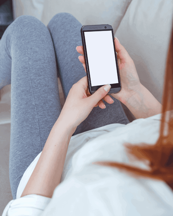 woman sitting on couch meal planning with phone