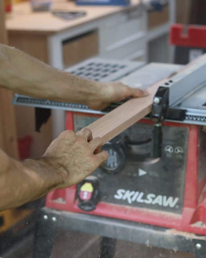 Man ripping oak board down using a table saw for a diy felt board.
